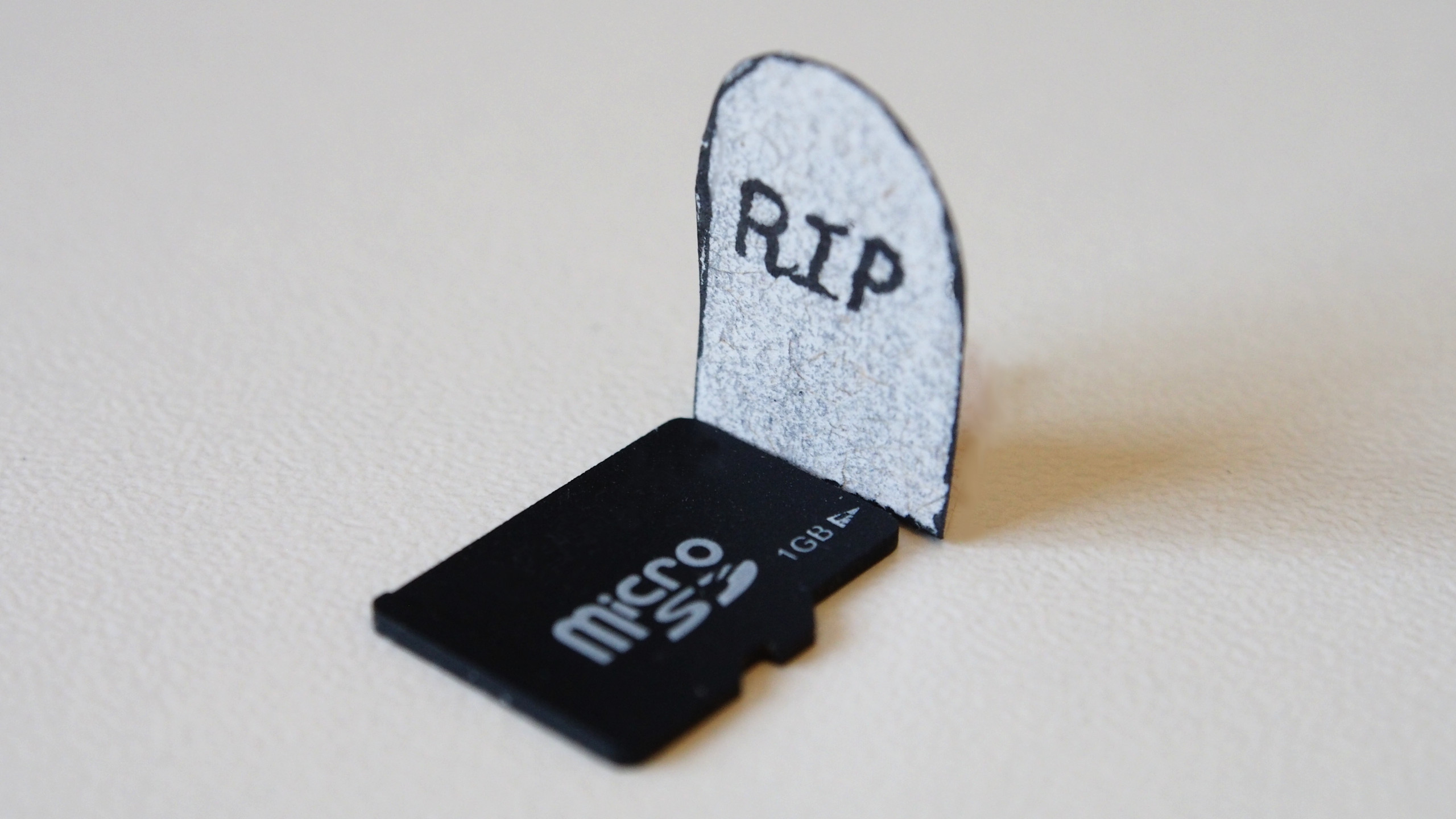 A micro-SD card lying in front of a tombstone.
